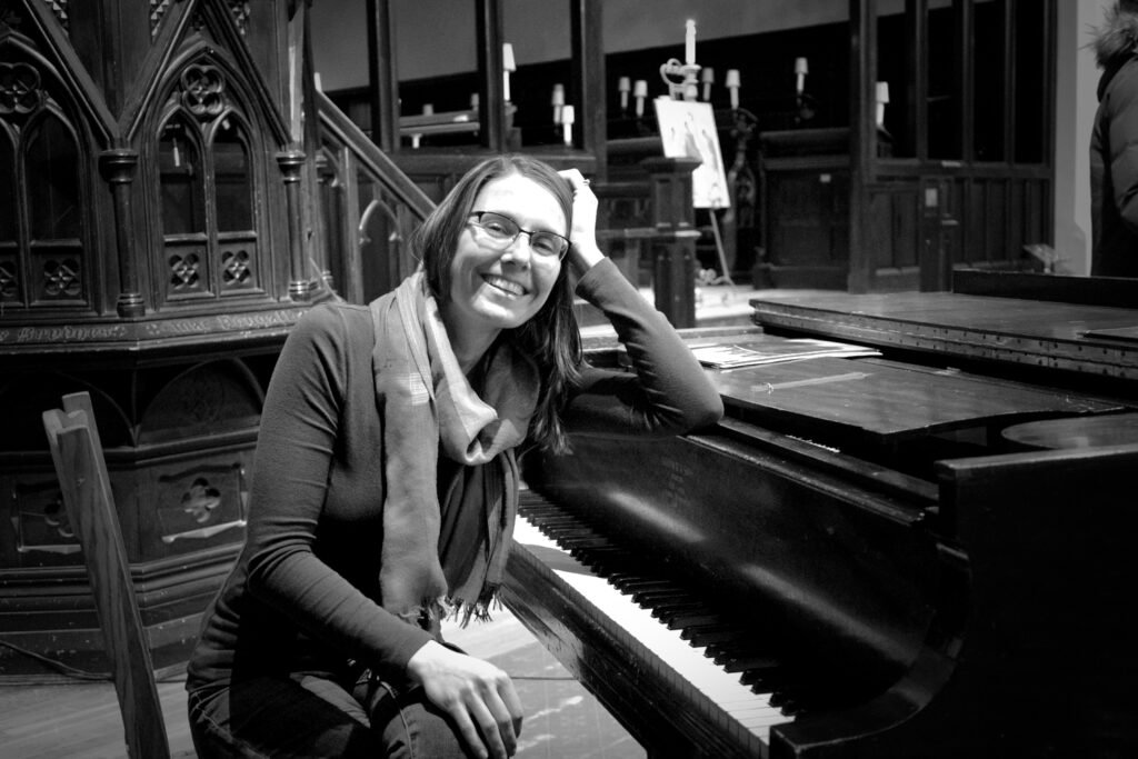 Trish Vrolijk sitting at a piano and smiling.